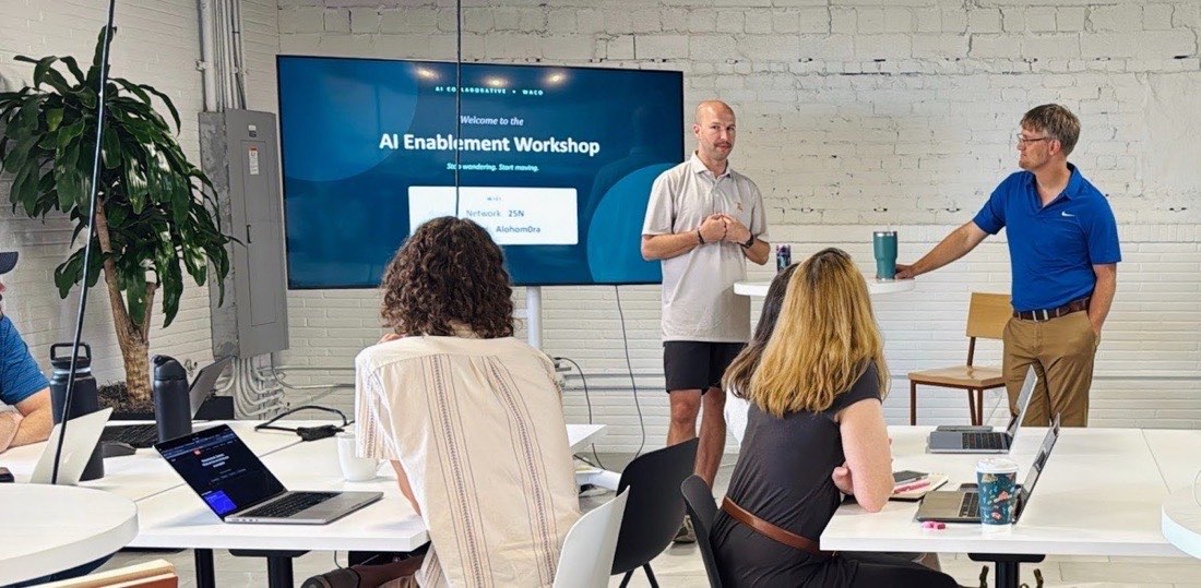 Attendees seated at tables facing the opening slide of the AI Enablement Workshop